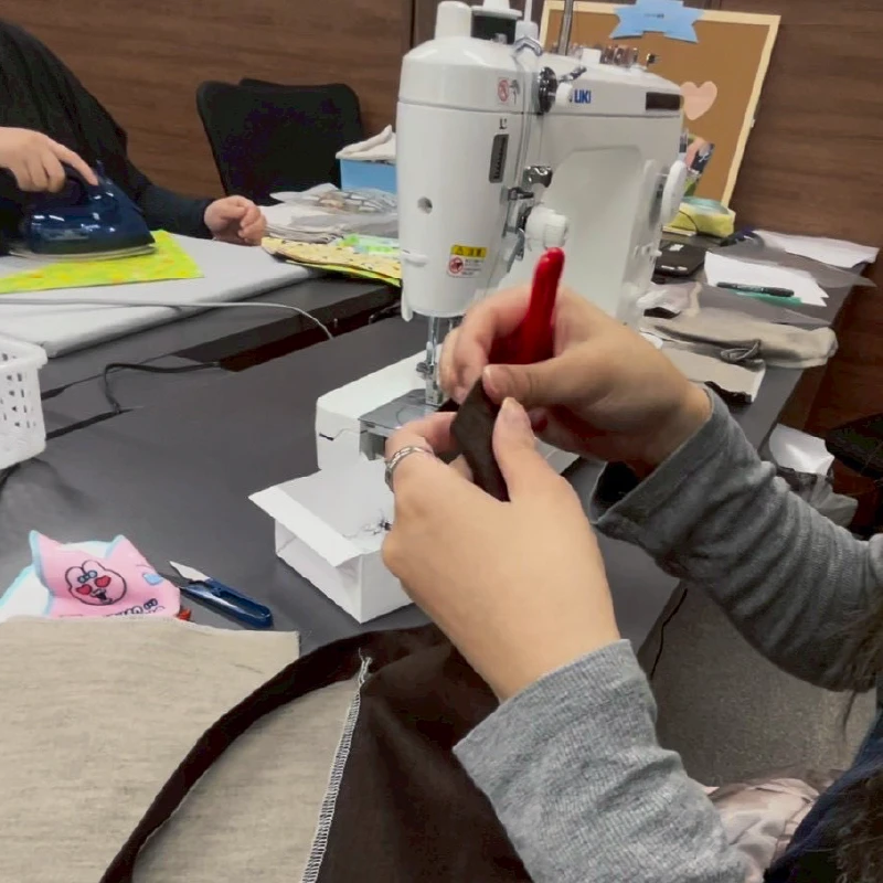 手提げバッグ制作のために素材のカット位置を確認する利用者さん