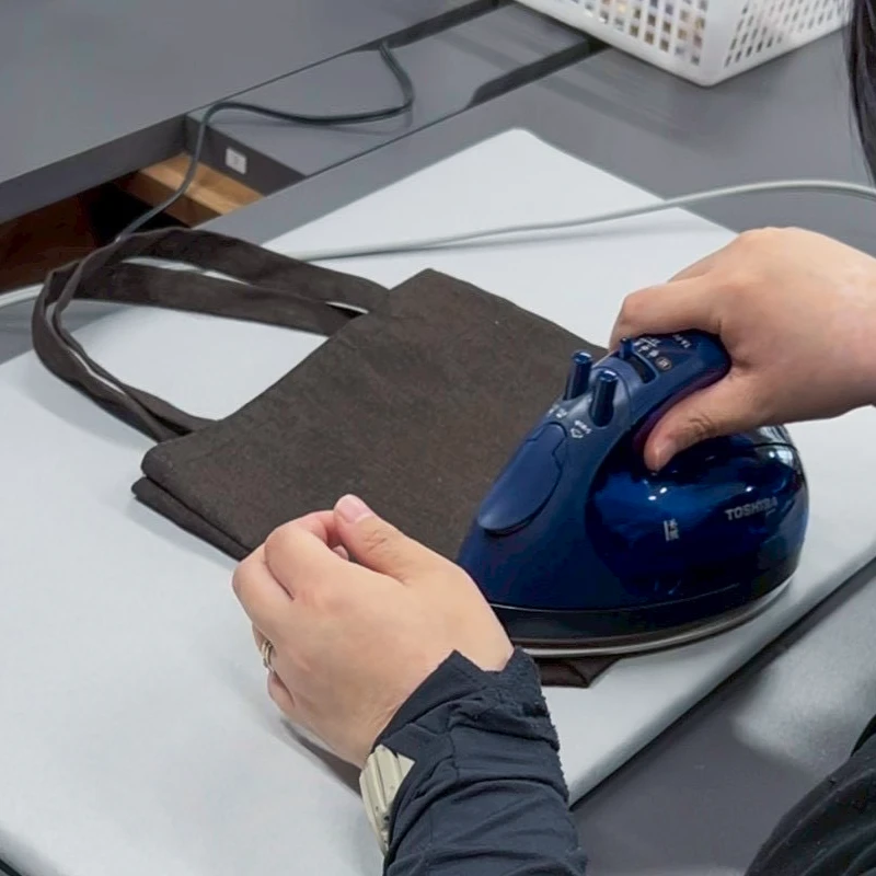 完成直前の手提げバッグにアイロンをかける利用者さん