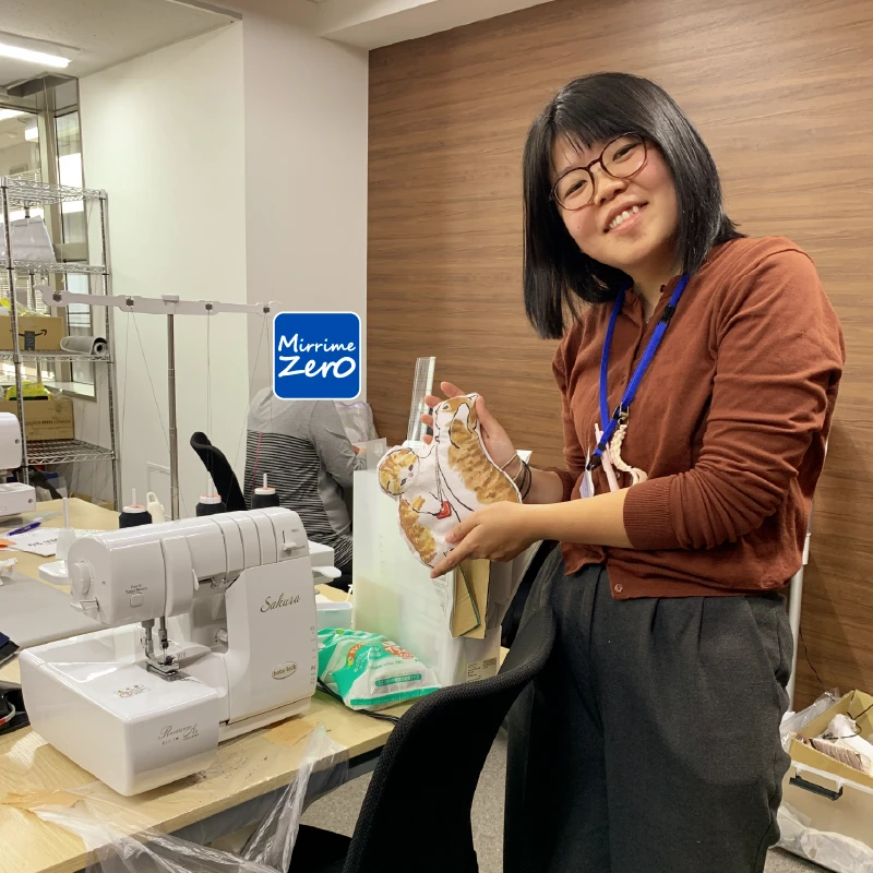 手に猫柄の猫用のクッションを持つ職員